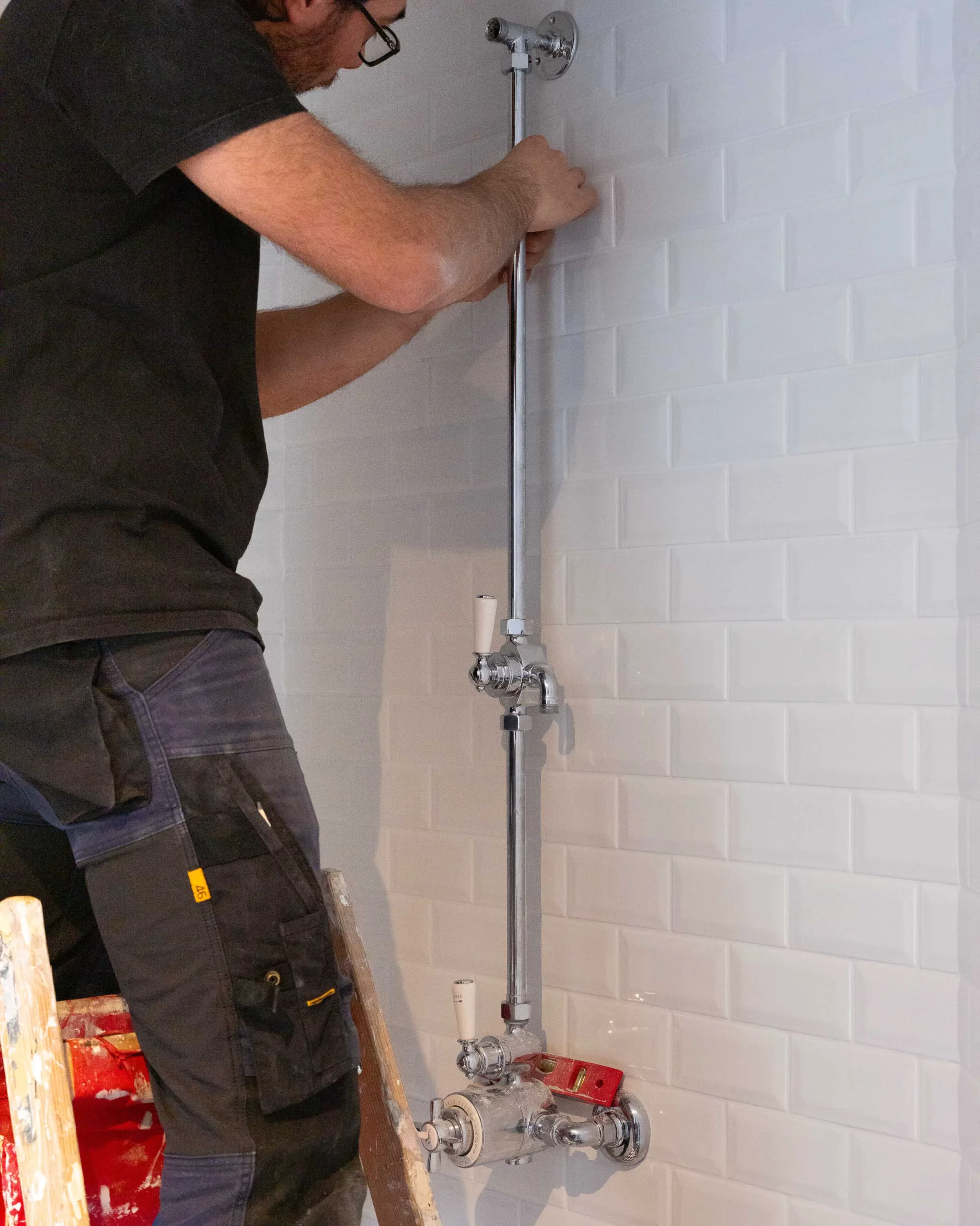 Raccords de plomberie apparents sur un mur carrelé, en cours d’intervention.