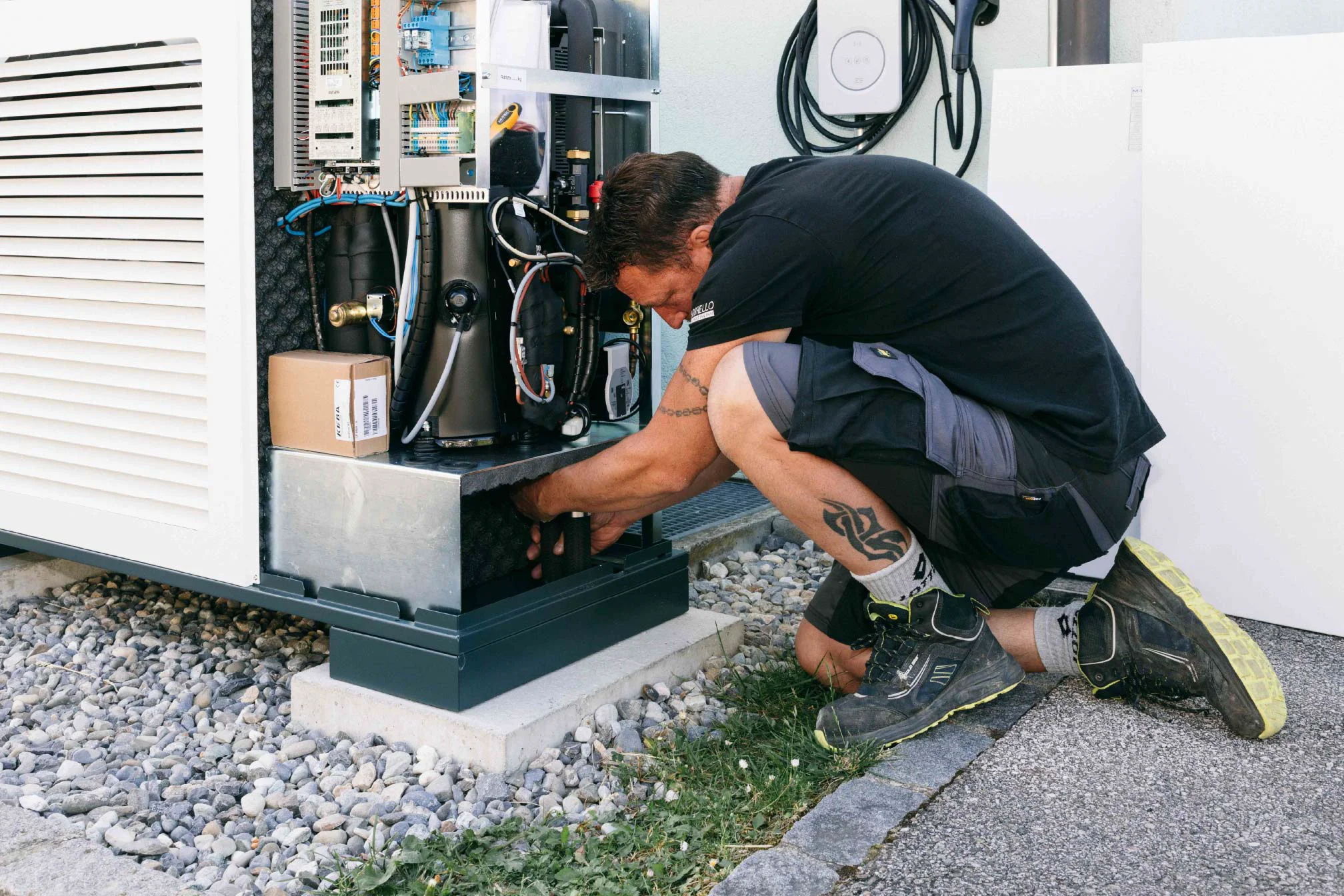 Personne intervenant sur une armoire technique extérieure ouverte avec câbles, panneaux et composants visibles
